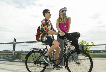 Glückliches junges Paar zusammen auf einem Fahrrad - UUF004883