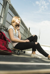 Teenager-Mädchen sitzt auf einem Skateboard und spricht mit einem Handy - UUF004919