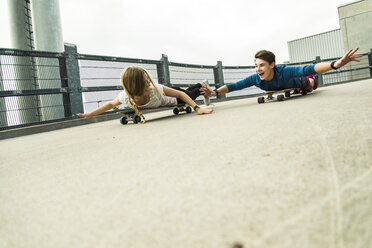 Enthusiastisches junges Paar fährt mit Skateboards bergab - UUF004890