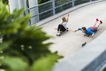 Enthusiastisches junges Paar fährt mit Skateboards bergab - UUF004891