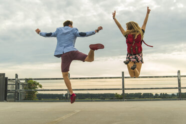 Enthusiastisches junges Paar springt auf dem Parkdeck - UUF004911