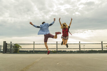 Enthusiastic young couple jumping on parking level - UUF004912