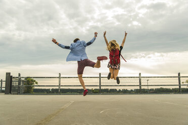 Enthusiastisches junges Paar springt auf dem Parkdeck - UUF004912