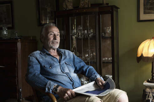 Älterer Mann mit Zeitung beim Entspannen zu Hause - MEMF000842
