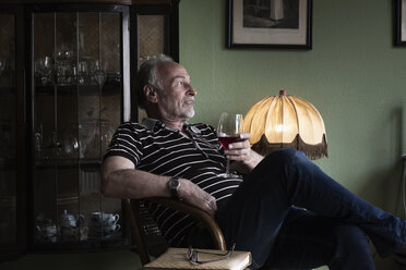 Senior man with glass of red wine relaxing at home - MEMF000847