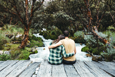 Peru, couple sitting arm in arm on a wooden bridge enjoying nature - GEMF000269