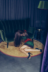 Young woman sitting on the floor in front of a couch - CHAF000532