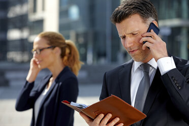 Geschäftsmann mit einem Tagebuch im Gespräch mit einem Mobiltelefon - CHAF000355