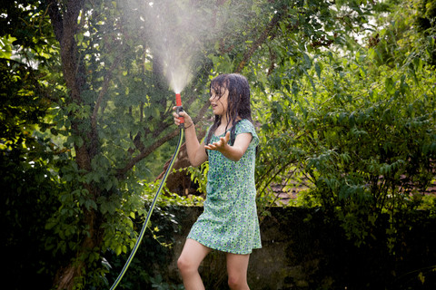 Girl cooling herself with garden hose stock photo