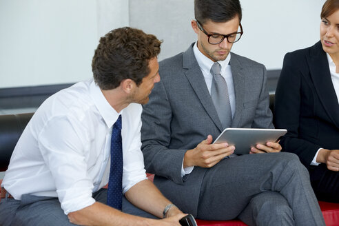 Drei Geschäftskollegen mit digitalem Tablet diskutieren in der Büro-Lobby - CHAF000377