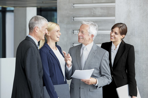 Fröhliche Geschäftskollegen bei der Besprechung von Dokumenten in der Bürolobby, lizenzfreies Stockfoto