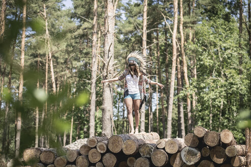 Junge Frau, als Indianer verkleidet, balanciert auf einem Holzstapel - ASCF000207