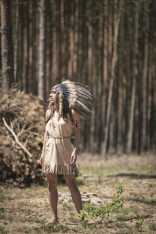 Junge Frau als Indianer verkleidet im Wald stehend, lizenzfreies Stockfoto