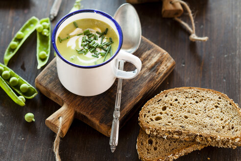 Emaille-Tasse mit Erbsensuppe mit Schnittlauch und Brotscheiben - SBDF002139