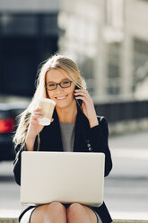 Businesswoman with coffee to go using laptop and cell phone - CHAF000548