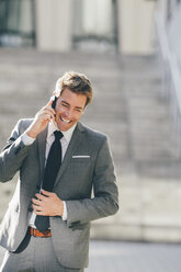 Lächelnder Geschäftsmann, der im Freien mit seinem Handy telefoniert - CHAF000553