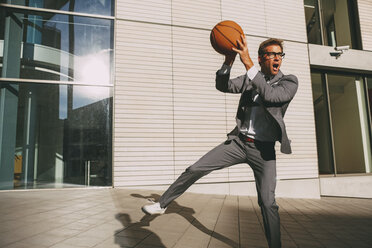 Businessman playing basketball outdoors - CHAF000438