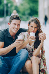 Lächelndes junges Paar beim Kaffeetrinken im Freien - CHAF000450