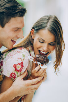 Glückliches junges Paar isst Schokoladenmuffin - CHAF000452