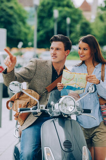 Junger Mann auf Motorroller dirigiert Frau mit Karte - CHAF000560