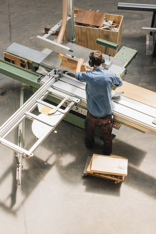 Schreiner bei der Arbeit mit der Säge in der Werkstatt, lizenzfreies Stockfoto