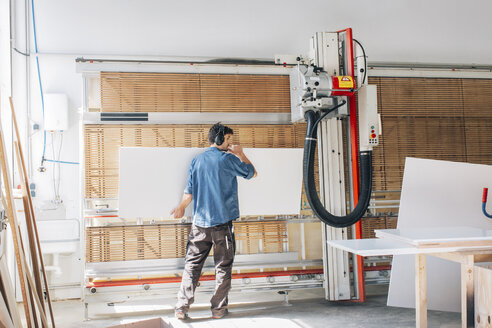 Carpenter cutting wood in workshop with machine - JUBF000045