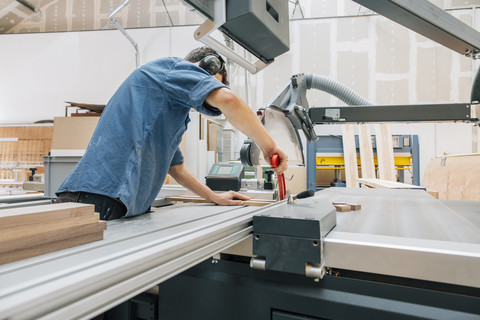 Schreiner bei der Arbeit mit der Säge in der Werkstatt, lizenzfreies Stockfoto