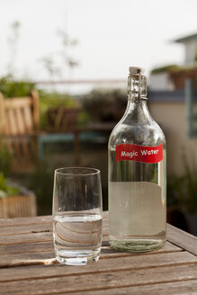 Wasserglas und Flasche auf dem Tisch im Garten - HCF000125