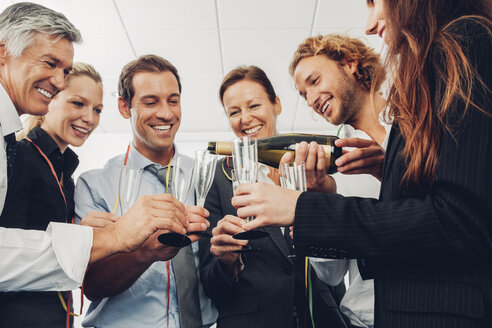 Gruppe von Geschäftsleuten, die im Büro mit Champagner anstoßen - CHAF000483