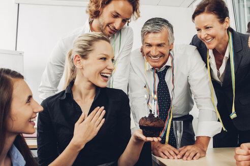 Lächelnde weibliche Führungskraft, die im Büro mit Kollegen ihren Geburtstag feiert - CHAF000484