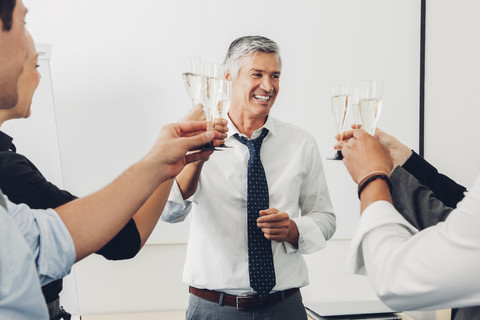 Gruppe von Geschäftsleuten, die im Büro mit Champagner anstoßen, lizenzfreies Stockfoto