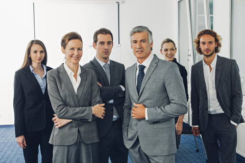 Eine Gruppe von Geschäftsleuten steht in einem Büro und schaut in die Kamera, lizenzfreies Stockfoto