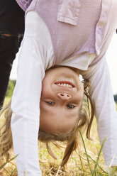 Porträt eines glücklichen kleinen Mädchens im Handstand auf einer Wiese - STKF001327