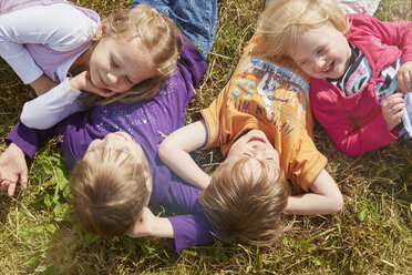 Vier kleine Kinder liegen auf einer Wiese und genießen die Sonne - STKF001328