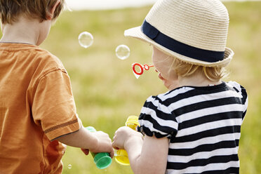 Back view of two little children blowing soap bubbles - STKF001330