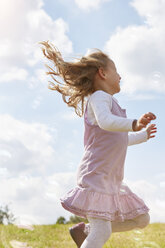 Little girl jumping on a meadow trying to catch soap bubbles - STKF001337