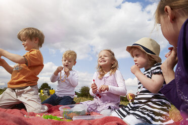 Kinder sitzen auf einer Decke und essen Süßigkeiten - STKF001345