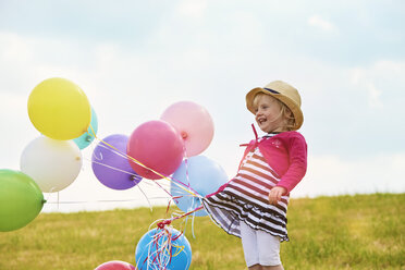 Kleines Mädchen mit Luftballons auf einer Wiese - STKF001348