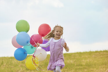 Kleines Mädchen mit Luftballons läuft auf einer Wiese - STKF001354