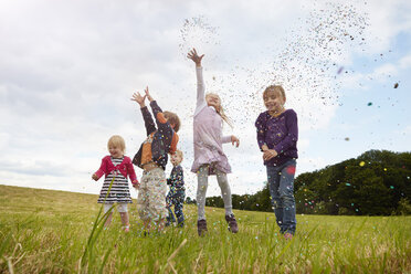 Five little children throwing confetti on a meadow - STKF001356
