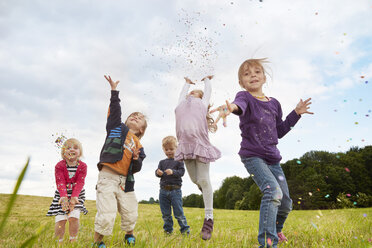 Five little children throwing confetti on a meadow - STKF001357