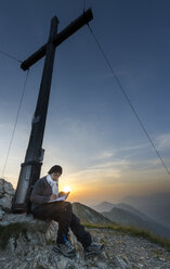 Austria, Tyrol, woman on summit writing in summit book - MKFF000237