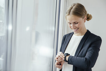 Smiling young businesswoman checking her smart watch - MFF001853