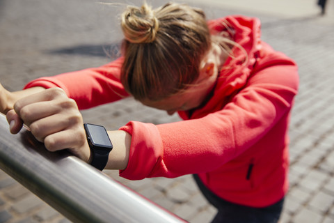 Junge sportliche Frau mit Smartwatch, die sich streckt, lizenzfreies Stockfoto