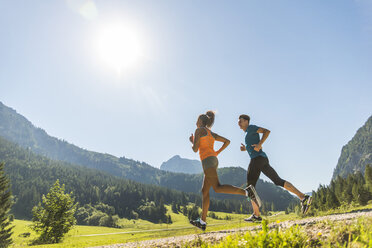 Austria, Tyrol, Tannheim Valley, young couple jogging in alpine landscape - UUF004922