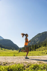 Österreich, Tirol, Tannheimer Tal, junge Frau joggt in alpiner Landschaft - UUF004924