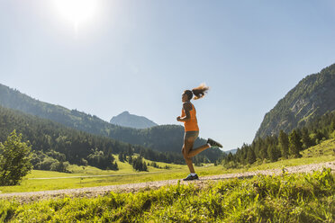 Österreich, Tirol, Tannheimer Tal, junge Frau joggt in alpiner Landschaft - UUF004925
