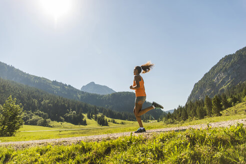 Österreich, Tirol, Tannheimer Tal, junge Frau joggt in alpiner Landschaft - UUF004925