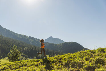 Austria, Tyrol, Tannheim Valley, young woman jogging in alpine landscape - UUF004926