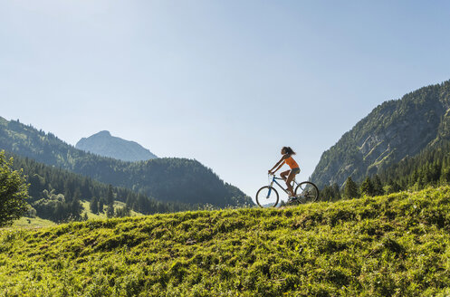 Österreich, Tirol, Tannheimer Tal, junge Frau auf Mountainbike in alpiner Landschaft - UUF004931